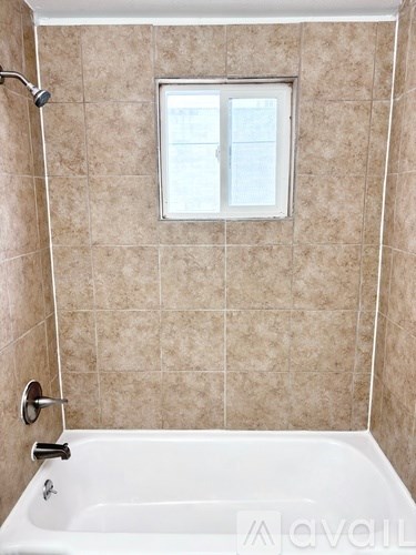 A bathroom with a tub and a window.
