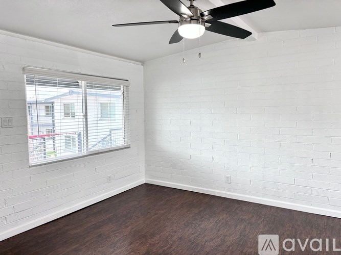 A room with a ceiling fan and a window with blinds.