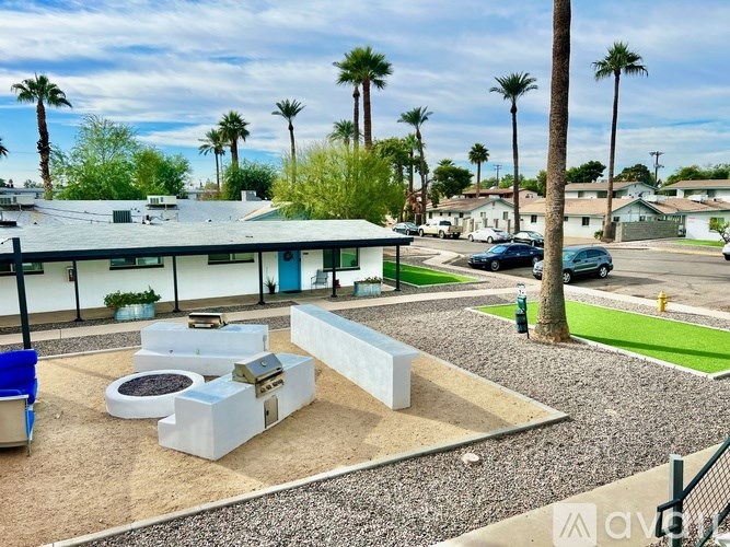 A sunny day in a residential area with a blue dumpster and a white bench.
