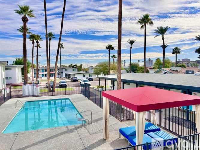 A pool surrounded by palm trees and a red canopy.