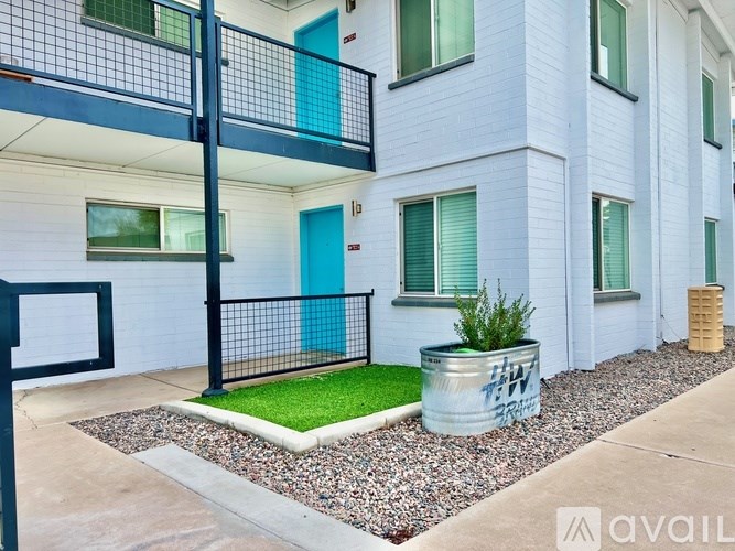 A white building with a blue door and a black fence.