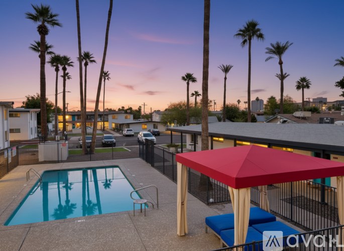 A pool surrounded by palm trees and a red umbrella.