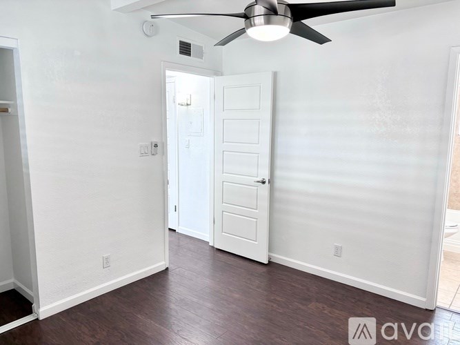 A room with a white door and a ceiling fan.
