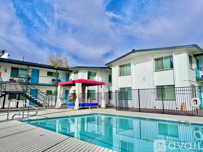 A pool in front of a white and blue building with a red awning.