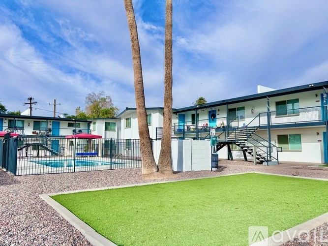 A playground area with a slide and a palm tree in front of a building.