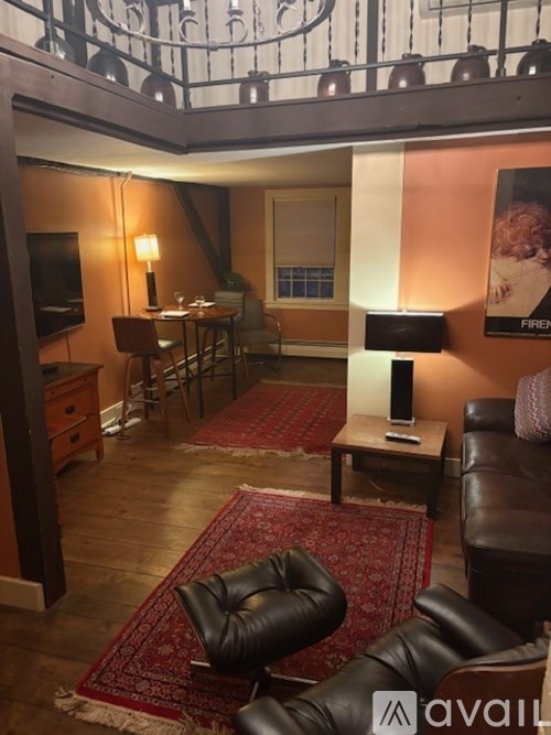 A living room with a black leather chair and a red rug.