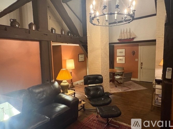 A living room with a black leather couch and a black chair.