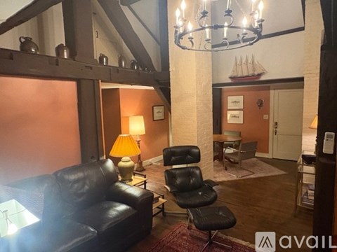 A living room with a black leather couch and a black chair.