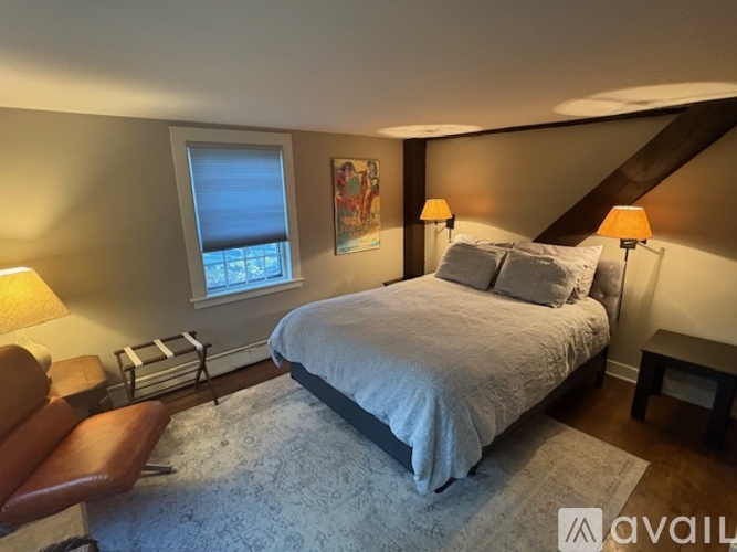 A bedroom with a large bed and a chair.