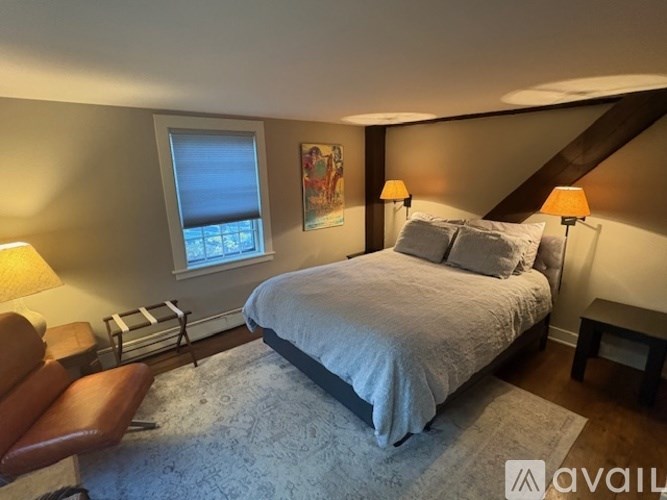 A bedroom with a large bed and a chair.