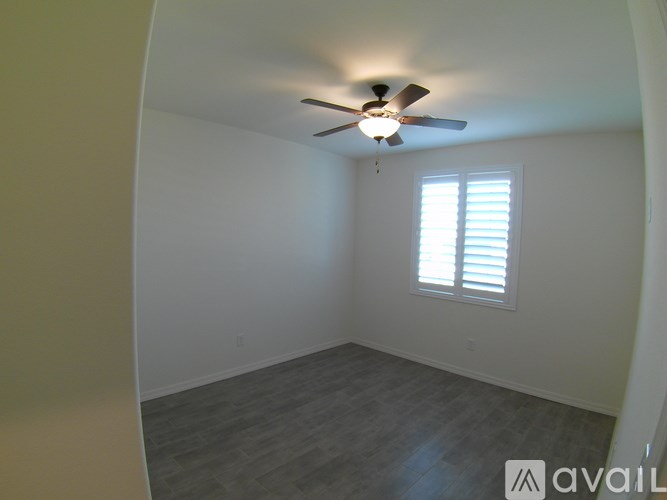 A room with a ceiling fan and a window with blinds.