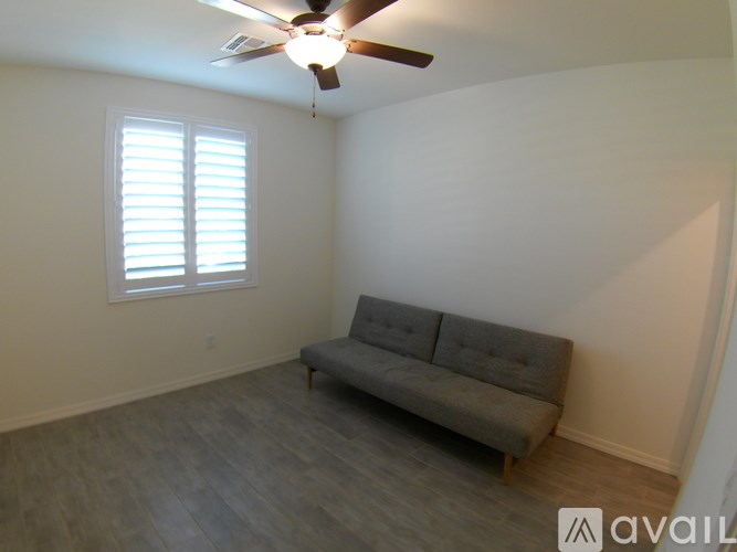 A living room with a grey couch and a ceiling fan.