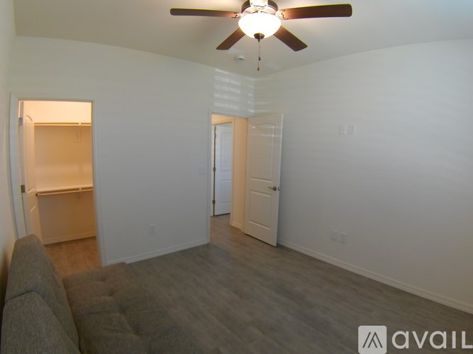 A living room with a ceiling fan and a grey couch.
