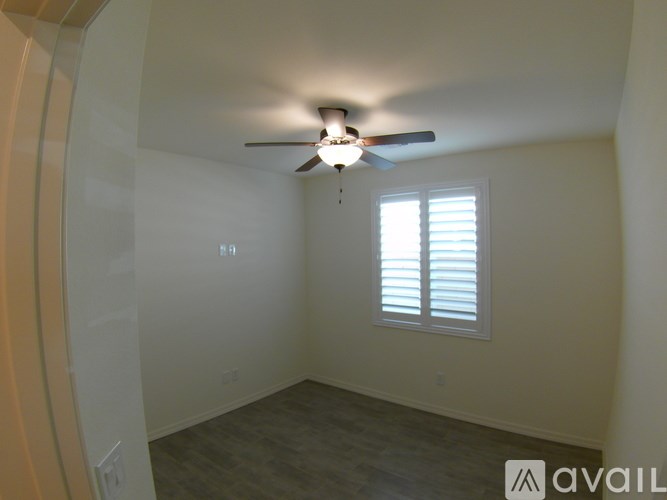A room with a ceiling fan and a window with blinds.