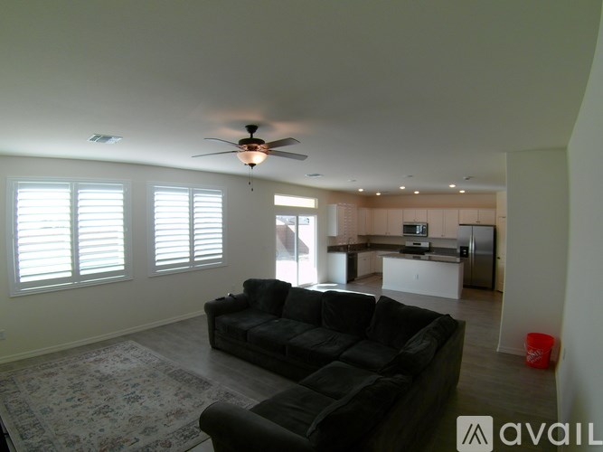 A living room with a black couch and a ceiling fan.