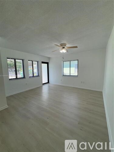 A spacious room with a ceiling fan and large windows.