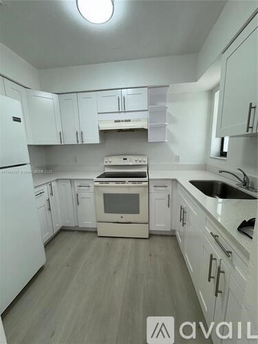 A kitchen with white appliances and cabinets.