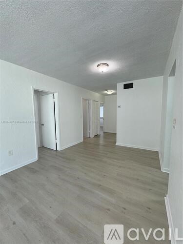 A room with wooden flooring and white walls.