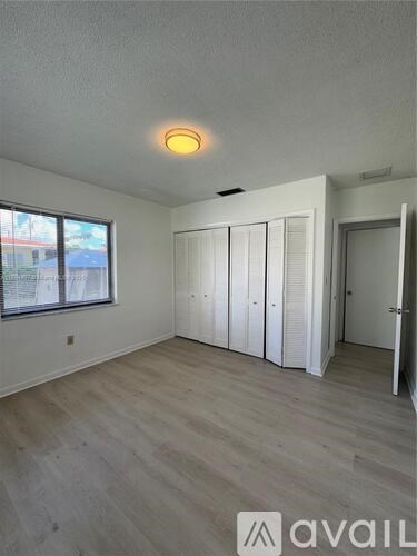 A room with a window and a wooden floor.
