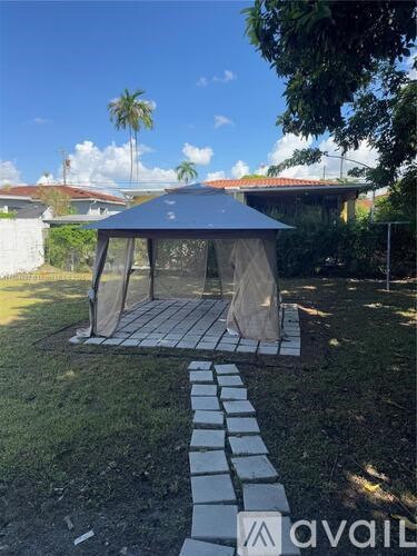 A gazebo-like structure with a roof and a walkway leading to it.