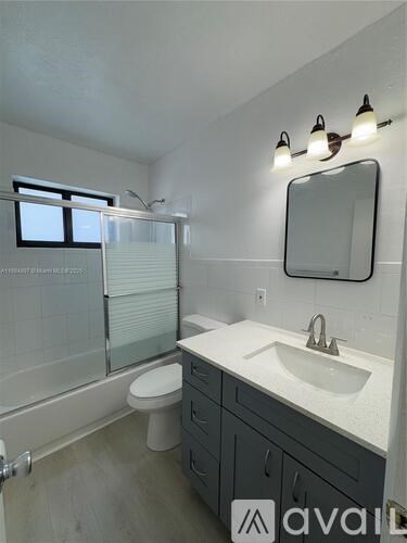 A bathroom with a sink, toilet, and mirror.