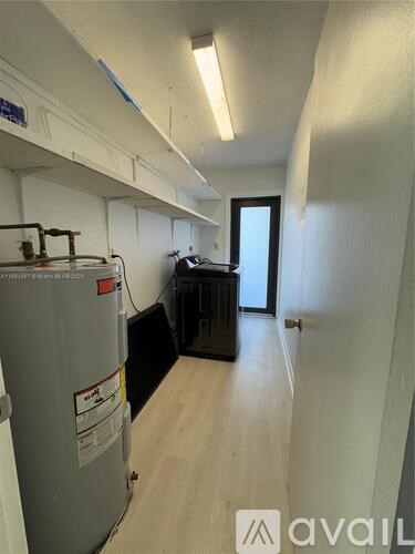 A room with a grey fridge and a black cabinet.