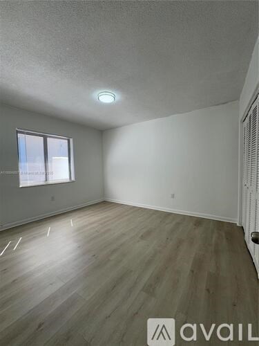 A room with wooden flooring and a window.