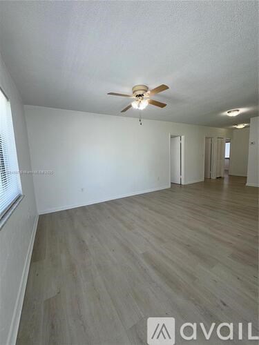 A room with a ceiling fan and lighting fixture, and a wooden floor.