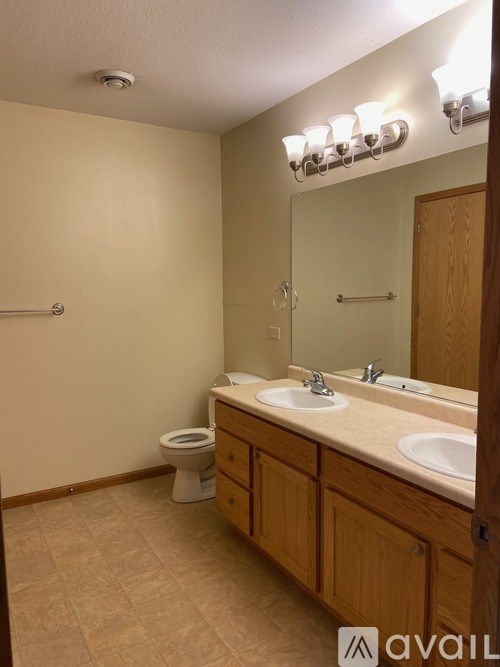 A bathroom with a toilet, sink, and mirror.