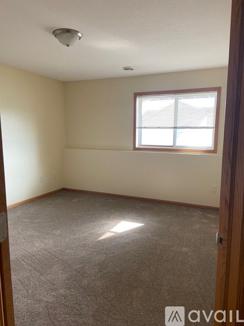 A room with a carpeted floor and a window with blinds.