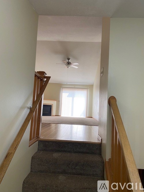 A staircase with a wooden railing leads to a living room.