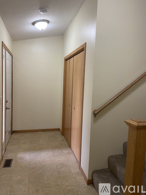 A hallway with a wooden door and stairs.