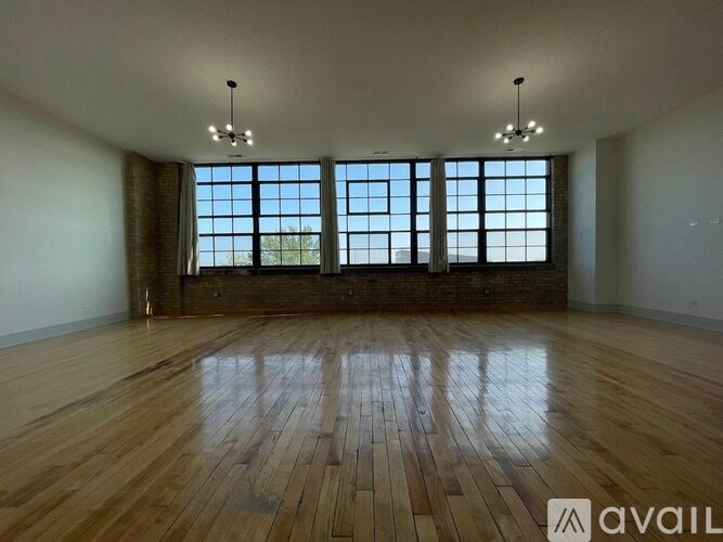 A spacious room with wooden floors and large windows.