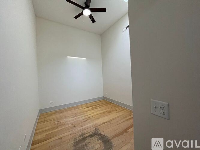 A room with a ceiling fan and wooden flooring.
