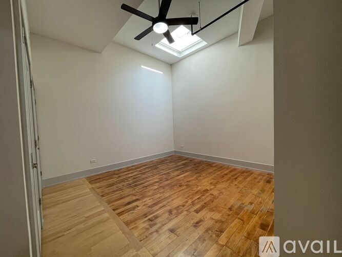 A room with wooden flooring and a ceiling fan with a light fixture.