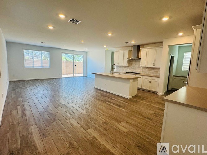 A spacious kitchen and living room with wooden flooring and white walls.
