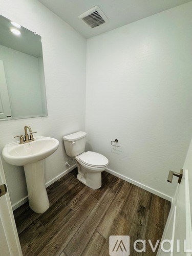 A bathroom with a toilet, sink, and mirror.