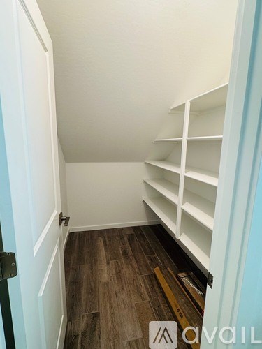 A white door is open to a hallway with shelves.
