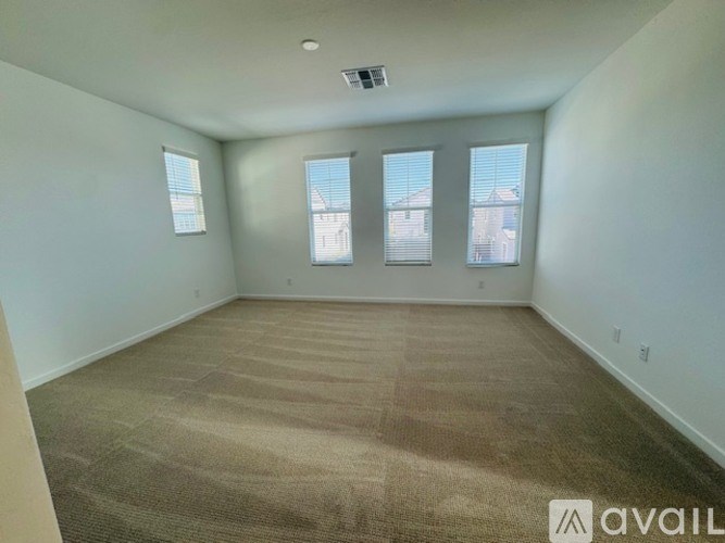 A room with carpeted floor and three windows.