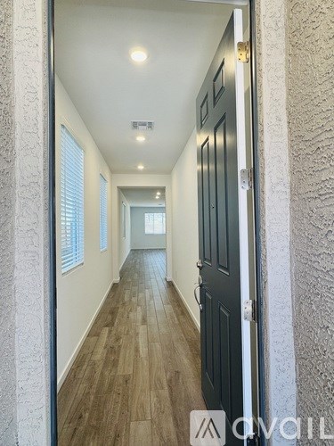 A hallway with wooden floors and a black door.