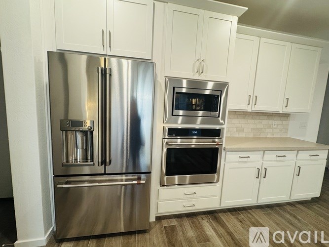 A spacious kitchen with wooden flooring and white cabinets.