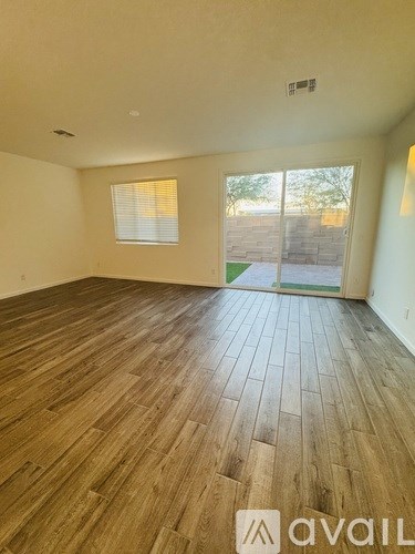 A room with wooden flooring and a window overlooking a backyard.