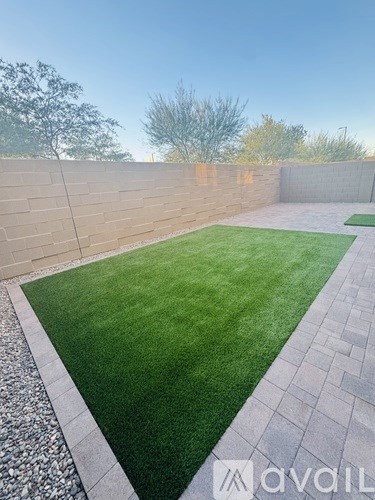 A backyard with a grassy area and a stone border.