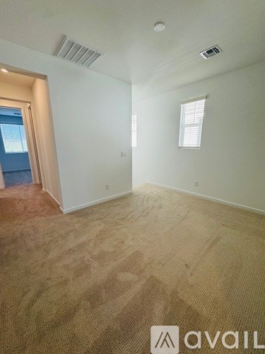A room with a carpeted floor and a window with blinds.