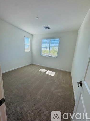 A room with a carpeted floor and two windows.