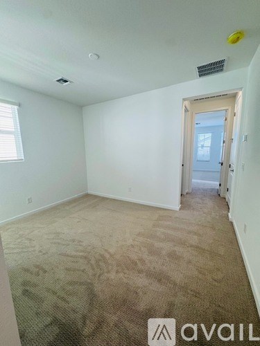 A room with beige carpet and a door leading to another room.