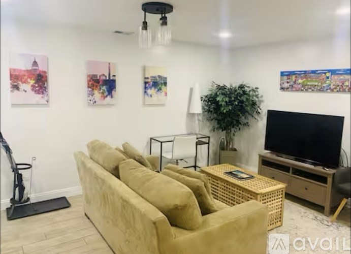 A living room with a beige sofa, a black TV, and a plant.