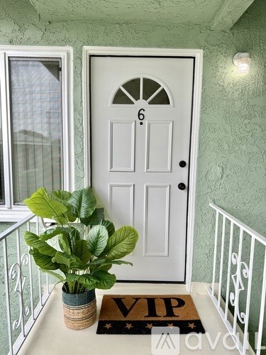 A white door with a number 6 on it and a plant in a pot.