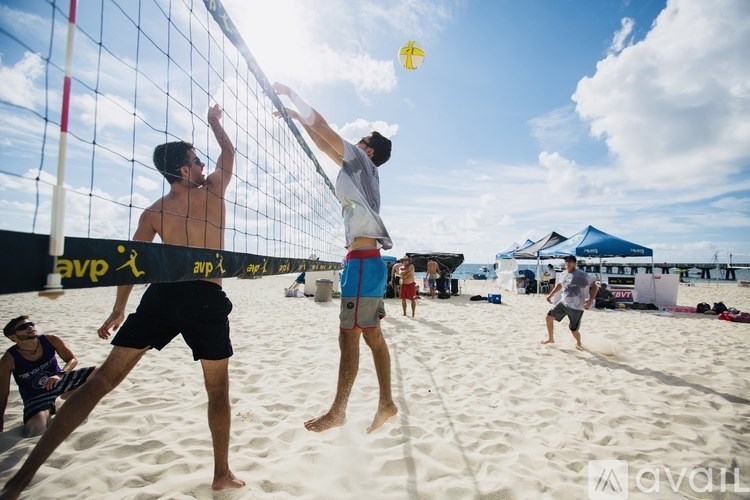 Two men playing beach volleyball with a yellow ball in the air.