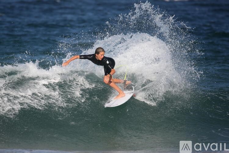 A surfer in a black wetsuit is riding a wave.